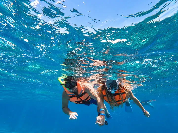 Two guests looking toward the camera below the water surface.
